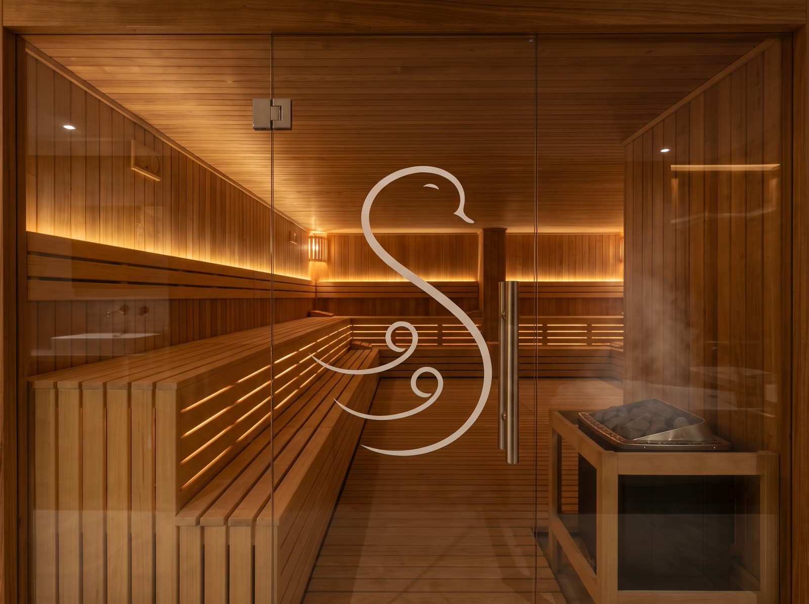 Dry sauna with cedar benches and a glass door etched with the swan